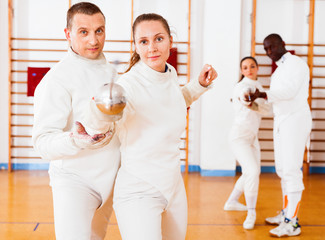 Woman fencer practicing new movements with trainer  at fencing room