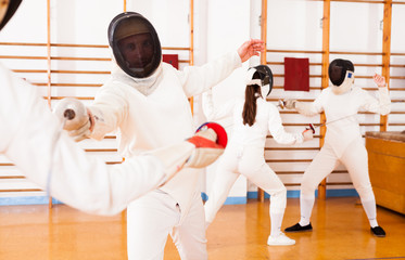 Athletes at fencing workout, practicing attack movements in duel