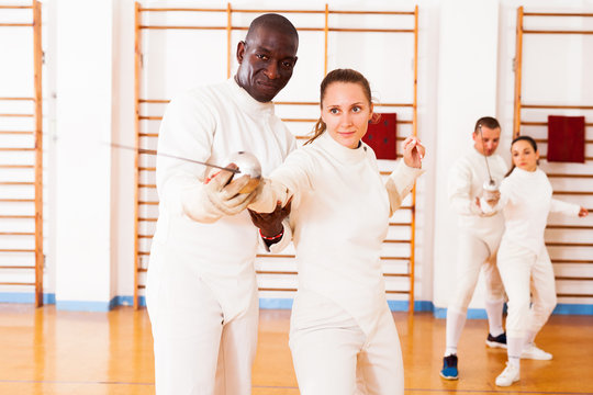 fencer practicing movements with african american trainer - Powered by Adobe