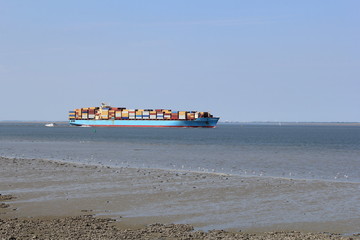 a large blue cargo ship navigates towards antwerp with low tide
