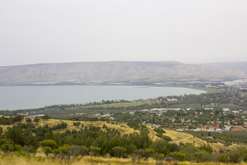 Fototapeta na wymiar The calm waters of the Sea of Galilee from the hills near the Town of Tiberias in early evening on a hazy day in May 2018 