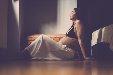 pregnant beautiful caucasian woman sitting on the floor and breathe to relax. new life concept at...