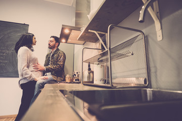 lovely couple she pregnant in the kitchen at home touching the belly and live with joy the wait of...