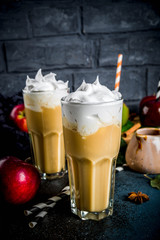 Spiced Caramel Apple or apple pie smoothie, organic autumn fruit cocktail with whipped cream, On a dark background, with apples, leaves, caramel sauce and a warm blanket. Copy space for text