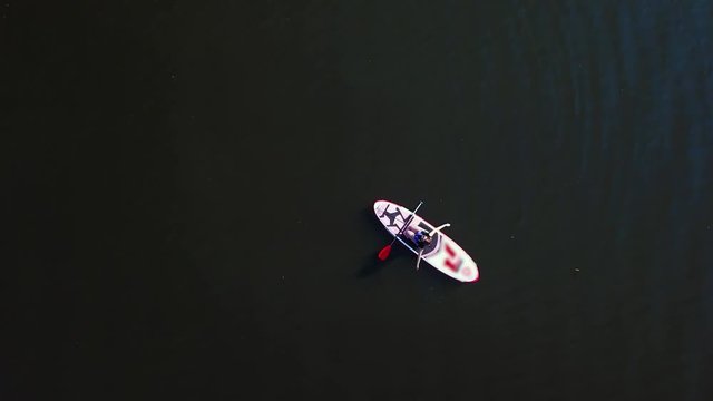 Young girl sits on a kayak sailing along the river