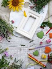 Seasonal decorative composition of flowers, berries, art and clerical materials, hearts made of felt on a background of light wood, top view. Congratulations on the holiday