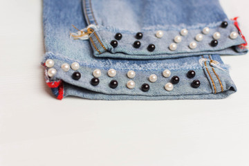 The design of jeans. Beads in the form of pearls are sewn to the jeans. Fashionable jeans.