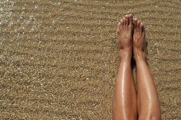 Female feet against the sea on the summer beach, time to travel. Empty place for a text