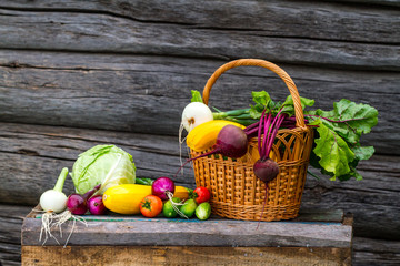 Fresh zucchini, cucumbers, onions, beets, tomatoes, cabbage in a basket on a wooden background....