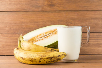 Melon and banana smoothie on wooden background.