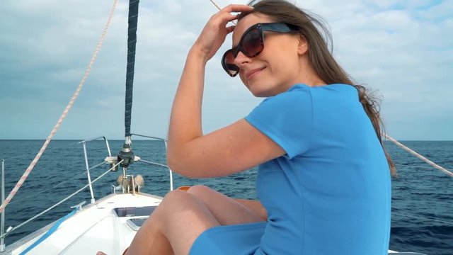 Woman in a blue dress rests aboard a yacht on summer season at ocean. Slow motion