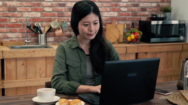 Slow motion woman typing in the kitchen.