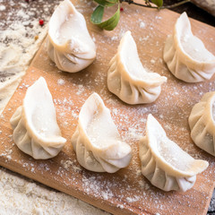 Pelmeni cooking on a board and wooden background, national Russian cuisine, vareniki, banner