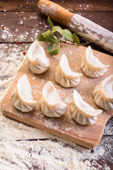 Pelmeni cooking on a board and wooden background, national Russian cuisine, vareniki, banner