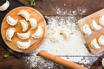 Pelmeni cooking on a board and wooden background, national Russian cuisine, vareniki - obrazy, fototapety, plakaty