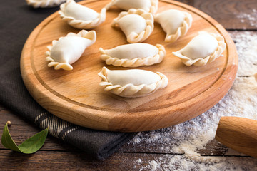 Pelmeni cooking on a board and wooden background, national Russian cuisine, vareniki