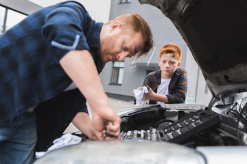 father and son repairing car with open hood
