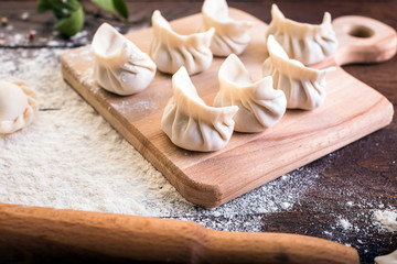 Pelmeni cooking on a board and wooden background, national Russian cuisine, vareniki