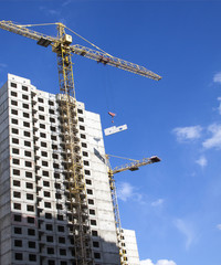 Crane and building under construction against blue sky.