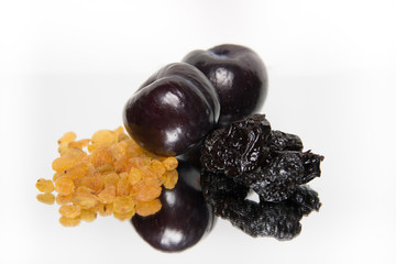 Raisins, plums and prunes on white background with reflection