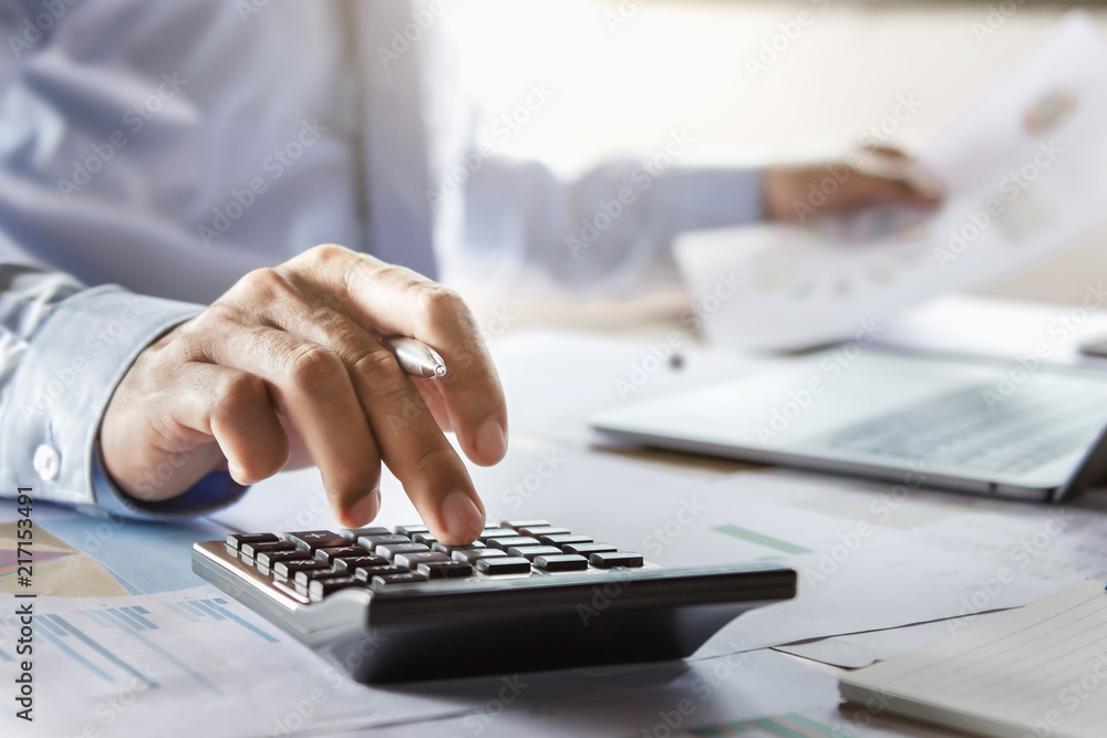 Fototapete accountant working on desk using calculator for calculate finance report in office