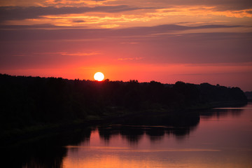 Obraz premium Bright, colorful evening landscape over the river Daugava of pink and purple tones. Dramatic sunset scenery in Latvia, Northern Europe.