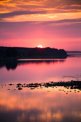 Naklejka premium Bright, colorful evening landscape over the river Daugava of pink and purple tones. Dramatic sunset scenery in Latvia, Northern Europe.