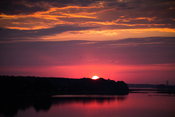 Fototapeta na wymiar Bright, colorful evening landscape over the river Daugava of pink and purple tones. Dramatic sunset scenery in Latvia, Northern Europe.