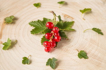 Close up of a little cluster of red currant and red currant leaves on wood  