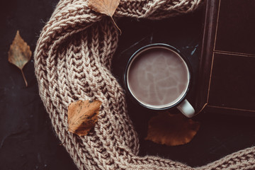 A cup of warm coffee and a book on a knitted scarf. Comfort. Autumn. Cozy weekend