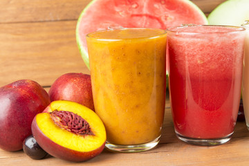 Varied fruit smoothies on wooden background.