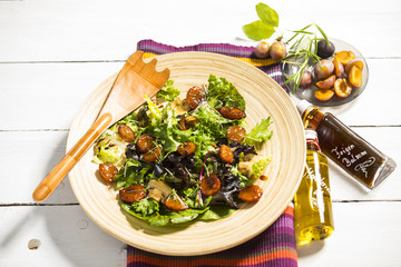 Salat mit gedünsteten Honig-Balsamico-Zwetschken (Zwetschgen), Champignons, Mandeln und Kresse auf Holzteller serviert