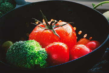  Tomaten und Broccoli, frisch gewaschen in einem dunklen Küchensieb