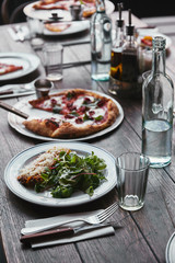 close-up shot of delicious pizza and lasagne on wooden table with water