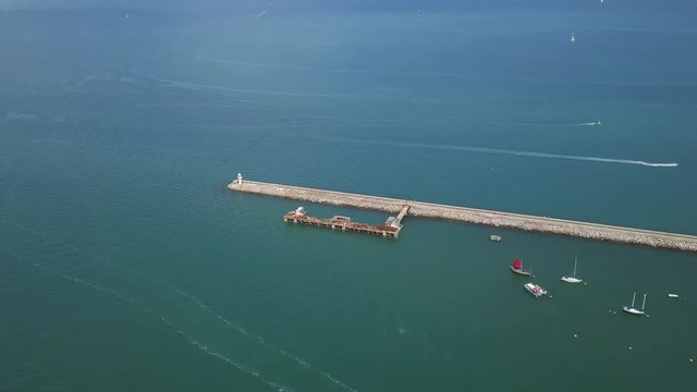 Sky view of breakwater and lighthouse in Brixham England. Speed boat racing on ocean water.