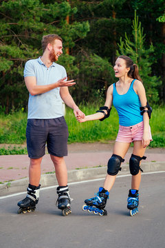 couple in love rollerblading in the summer in the park . a young and attractive woman and a handsome man on rollers