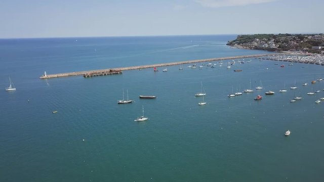 Aerial view of the breakwater and lighthouse in Brixham, England. Boats are docked near the harbour.