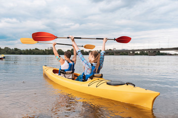 Winning the prize. Active athletic sportsmen sitting in yellow canoe feeling happy winning the prize