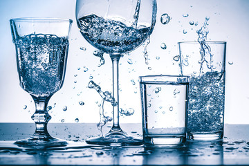 Viele Wasserspritzer mit Gläsern auf hellem  Hintergrund
