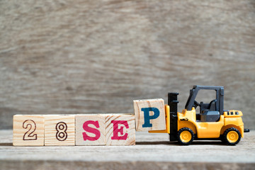 Toy forklift hold block P to complete word 28 sep on wood background (Concept for calendar date in month September)