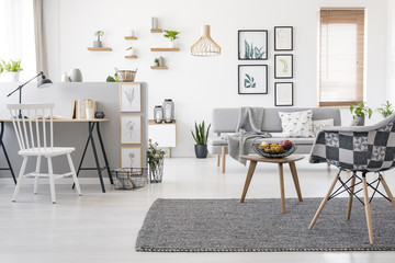 Checkered, stylish chair on a gray rug in a spacious, scandinavian living room interior with mock-up gallery above a sofa