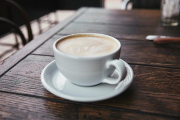 close-up shot of cup of coffee on rustic wooden table at restaurant