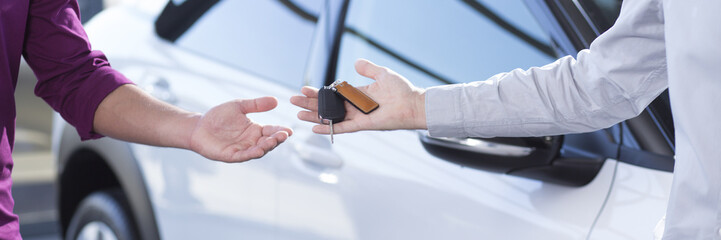 Panorama and close-up of car seller's hand with keys and buyer's hand after transaction
