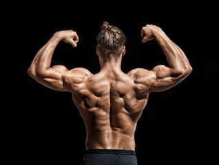 Young man showing his muscles. Rear view of bodybuilder with perfect physique on black background. Strength and motivation.