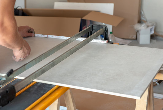 A man cutting stoneware tiles with tile cutter machine.