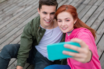 Our photo. Beautiful young woman taking a selfie while sitting together with her boyfriend