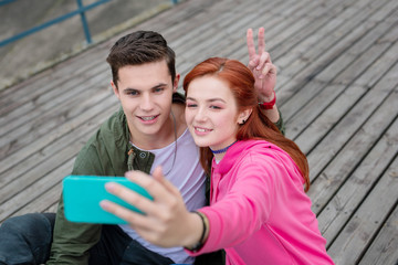 Sweet memories. Joyful young couple sitting together while taking a selfie