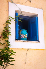 Assos, Kefalonia, Greece - July 2014: A ceramic pot sits in a pretty window in the village of Assos, Kefalonia