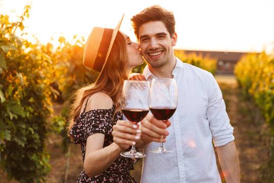 Cute happy loving couple outdoors drinking wine looking camera.