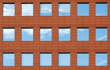 Minimalist facade of modern office building with square Windows. Finish is a dark red color